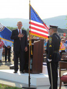WEB-Home-page-replace-Davids-220x293 a man in a suit standing at a podium with an american flag